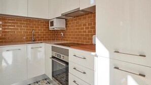 Una cucina con mobili bianchi, una parete a mosaico in mattoni e un forno integrato.