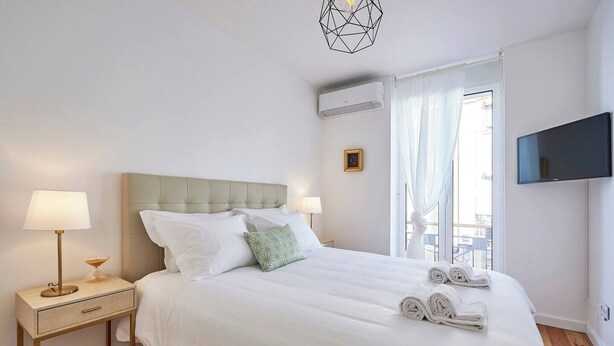 Una camera d'albergo con un letto, comodini, una TV e una finestra con tende.
