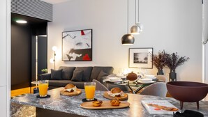 A modern kitchen with a marble countertop, a dining area with a table set for two, and a living room with a sofa and artwork. - Prime Location Contemporary Luxury Apartment W/ Ac & Elevator (Lisbon)