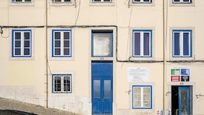 A building with multiple windows, a blue door, and a sign with text. - Historic Centre Modern Masterpiece W River Views (Lisbon)