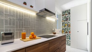 A modern kitchen with a white countertop, a built-in toaster, a cutting board with oranges, and a backsplash with geometric tiles. - Historic Centre Modern Masterpiece W River Views (Lisbon)