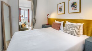 A modern hotel room with a large bed, a bedside table, a nightstand, and two framed artworks on the wall. - Historic Centre Modern Masterpiece W River Views (Lisbon)