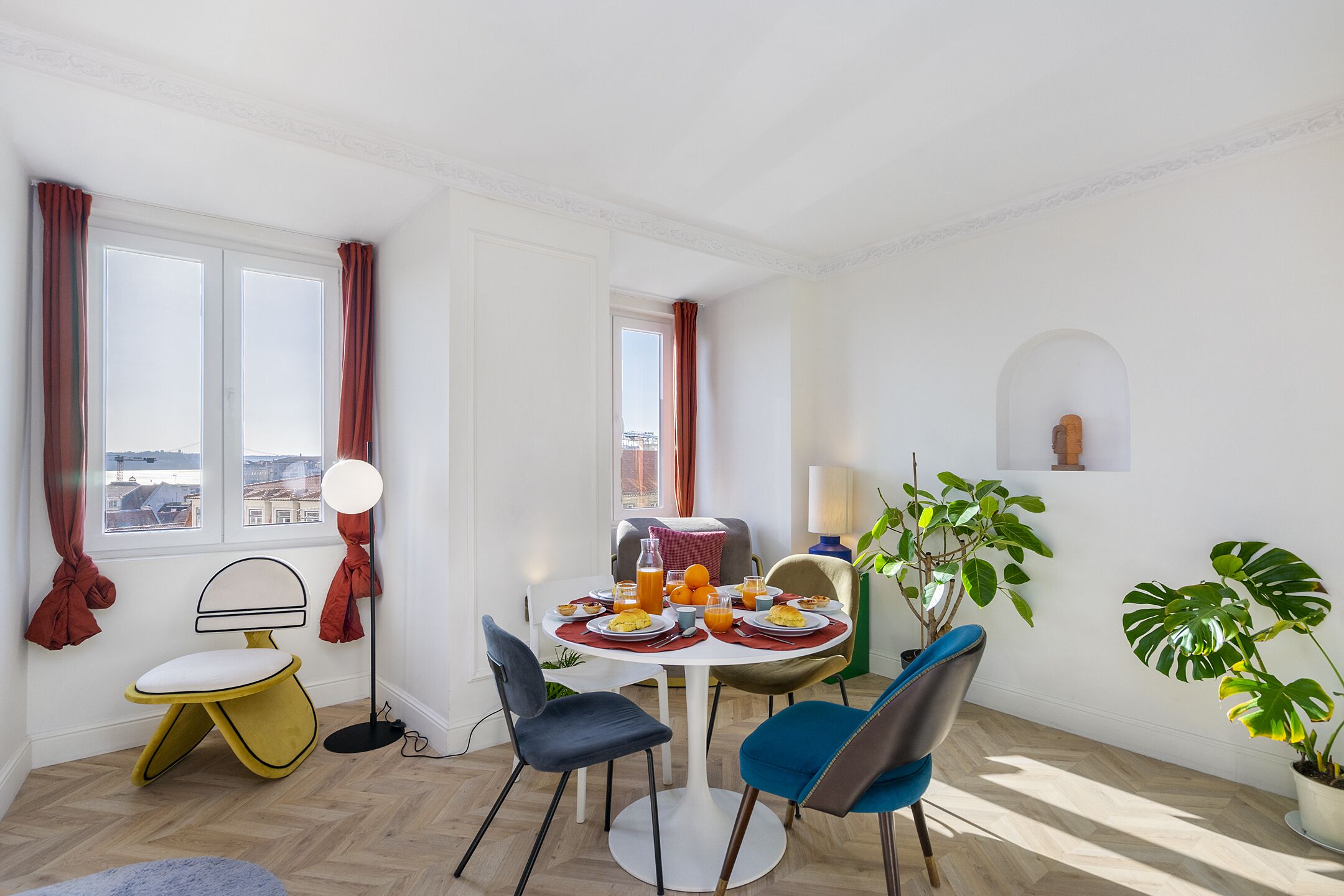 A dining area with a round table, chairs, a small sofa, and a potted plant.