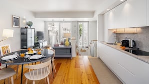 Una cocina moderna con armarios blancos, un comedor con una mesa redonda y vistas al exterior a través de una puerta de cristal.