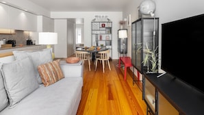 Una sala moderna con sofá, una mesa de comedor y televisor.