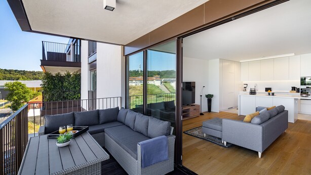A modern apartment with a balcony, a kitchen, and a living area with a sofa and a dining table. - History and Comfort Luxurious Living in Benfica (Lisbon)