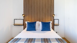 A neatly made bed with a plaid bedspread, two blue pillows, and a wooden slat headboard. - History and Comfort Luxurious Living in Benfica (Lisbon)