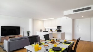 A modern living room with a sofa, TV, and dining area with a table set for breakfast. - History and Comfort Luxurious Living in Benfica (Lisbon)