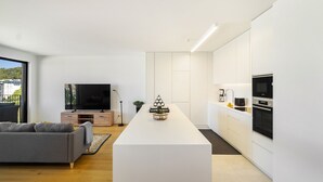 A modern kitchen with white cabinetry, a central island, and a built-in oven. - History and Comfort Luxurious Living in Benfica (Lisbon)