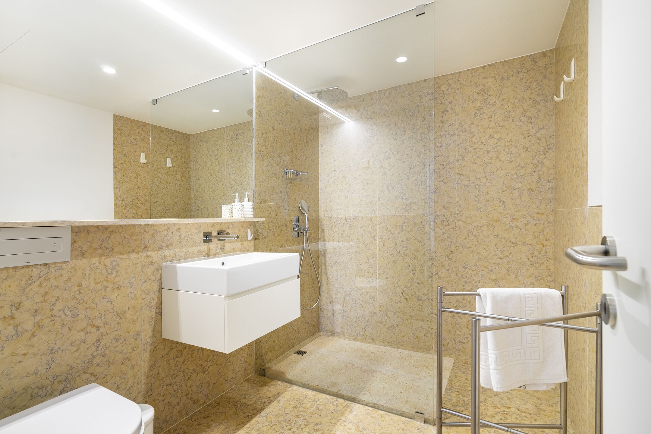 A modern bathroom with a glass-enclosed shower, a white sink, and a towel rack.