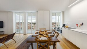 Een modern appartement met een eethoek, keuken en grote schuifdeuren met uitzicht op de stad.