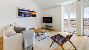 Een moderne woonkamer met een bank, salontafel en een televisie waarop 'NETFLIX' wordt weergegeven.