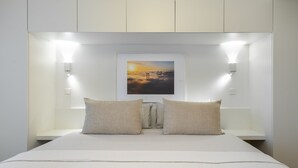 Een slaapkamer met een bed, twee bedlampen, een nachtkastje en een lijst aan de muur.