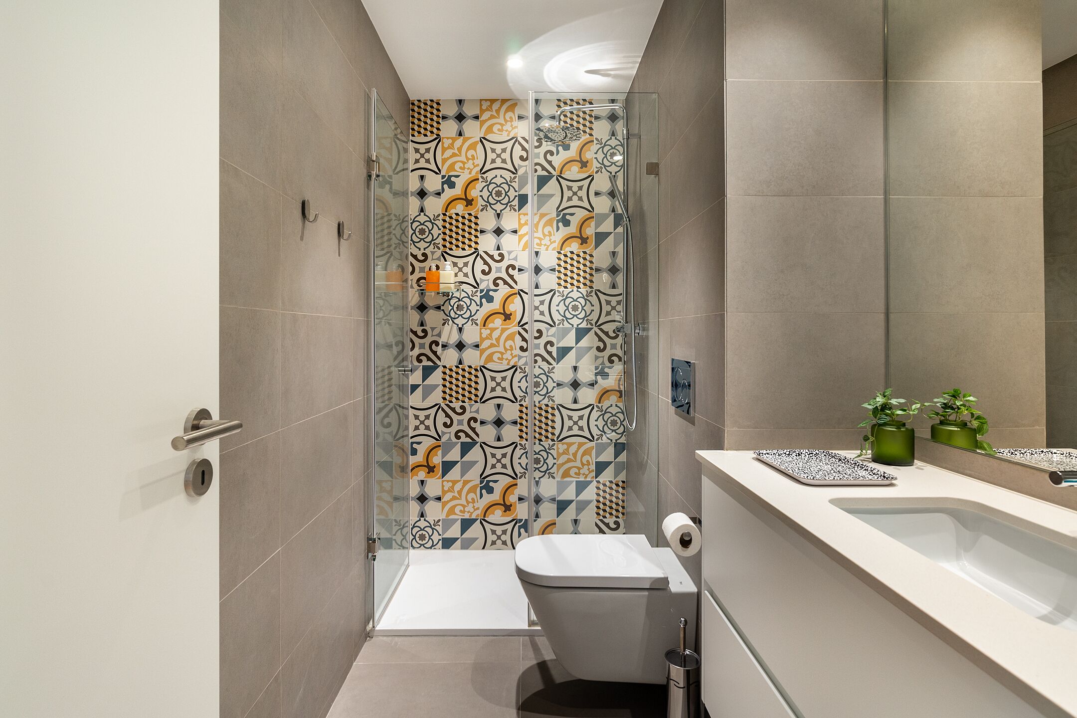 A modern bathroom with a shower, toilet, and sink.