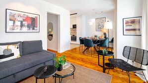 Ein modernes Wohnzimmer mit grauem Sofa, einem Couchtisch und einem Essbereich mit Stühlen und Tisch.