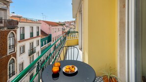 Ein Balkon mit Tisch, Topfpflanze und einer Auswahl an Gebäck.
