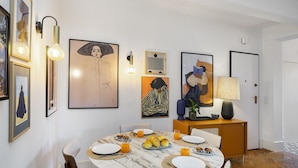 A dining area with a round table, chairs, plates, croissants, and orange juice. - Premium Alfama 2-Br Great For Remote Workers & Digital Nomads (Lisbon)