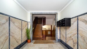 A marble-floored hallway leading to a staircase with a wooden finish. - Premium Alfama 2-Br Great For Remote Workers & Digital Nomads (Lisbon)