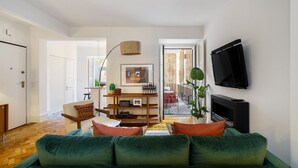 A modern living room with a green sofa, a flat-screen TV mounted on the wall, and a wooden coffee table. - Premium Alfama 2-Br Great For Remote Workers & Digital Nomads (Lisbon)