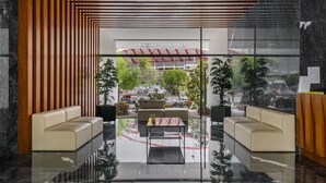 A modern lobby with a glass wall, two sofas, a coffee table, and a reception desk. - Urban Retreat W/Parking, Elevator & Ac By Benfica Stadium (Lisbon)