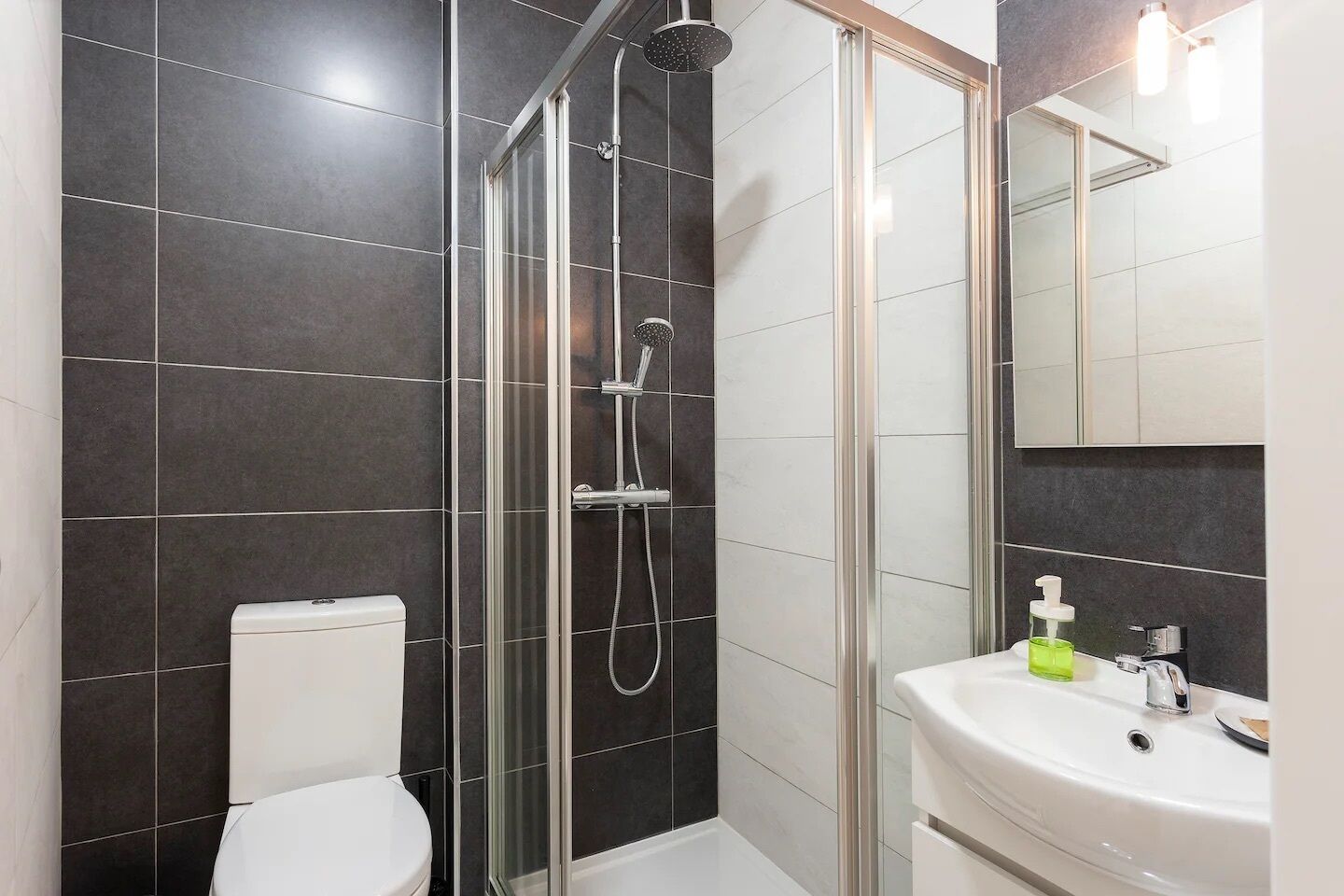 Une salle de bain moderne avec une douche à parois de verre, des toilettes et un lavabo avec un miroir au-dessus.