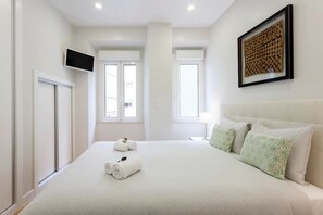 A hotel room with a large bed, two windows, a flat-screen TV, and a framed artwork on the wall. - Alfama Spacious 2-Bed Near Feira Da Ladra (Lisbon)