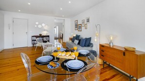 A modern living room with a glass dining table, a sofa, and a wooden cabinet.