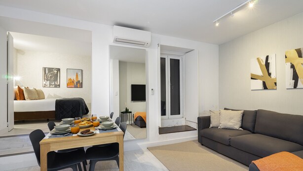 A modern living room with a sofa, a dining table with chairs, and a bed in the background. - Lisbon'S Best Kept Secret: 2-Bed W/Ac & Patio (Lisbon)