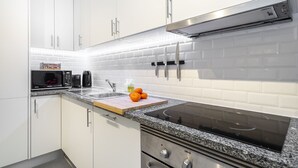 A modern kitchen with white cabinets, a granite countertop, a built-in microwave, a stove, and a cutting board with oranges. - Lisbon'S Best Kept Secret: 2-Bed W/Ac & Patio (Lisbon)