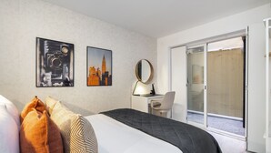 A hotel room with a bed, a desk, a chair, a large mirror, and a sliding glass door leading to an outdoor area. - Lisbon'S Best Kept Secret: 2-Bed W/Ac & Patio (Lisbon)