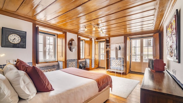 A bedroom with a large bed, wooden ceiling, and a view of the outside through a door. - Lisbon Gem Timeless Elegance And Modern Comfort (Lisbon)