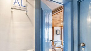 A hallway with a blue door leading to a room with a bed and a clock on the wall. - Lisbon Gem Timeless Elegance And Modern Comfort (Lisbon)