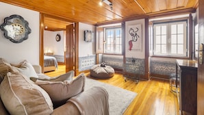 A cozy living room with a wooden ceiling, a sofa, a coffee table, a rug, and a dining area with a bar. - Lisbon Gem Timeless Elegance And Modern Comfort (Lisbon)