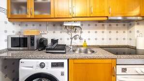 A kitchen with wooden cabinets, a microwave, a coffee maker, a sink, and a washing machine. - Lisbon Gem Timeless Elegance And Modern Comfort (Lisbon)
