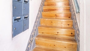A wooden staircase with a patterned railing and a blue mailbox on the wall. - Lisbon Gem Timeless Elegance And Modern Comfort (Lisbon)
