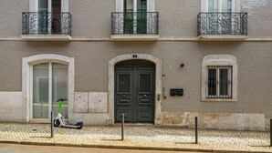 Un edificio con dos puertas, un ventanal pequeño y un balcón con barandilla de metal.