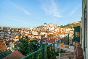 A balcony with a table, chairs, and a glass of orange juice. - Mouraria Modern Living Breathtaking Views & Ac (Lisbon)
