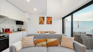 A modern living space with a grey sofa, striped cushions, a kitchen with a microwave, and a dining area with a table set for breakfast. - C314 Riverside View Premium Apartment w/ AC & Terrace (Porto)