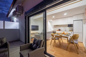 Cocina moderna con alacenas blancas, microondas y refrigerador. Cuenta con un comedor con mesa y sillas, además de un balcón con mobiliario de mimbre.