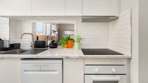 Eine moderne Küche mit weißen Schränken, einem Geschirrspüler, einem Backofen und einer schwarzen Induktionskochplatte.