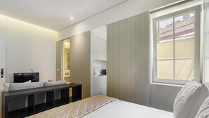 Et moderne hotelværelse med seng, sengebord, fjernsyn og et vindue med udsigt.