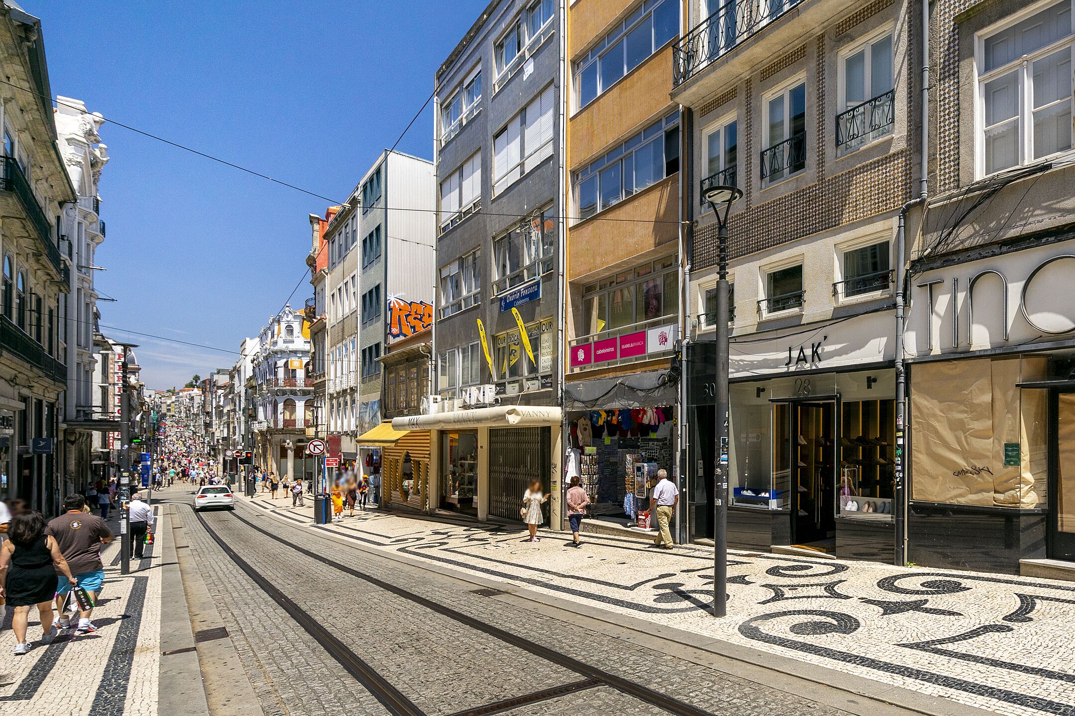 A street with buildings, shops, and a tram line.
