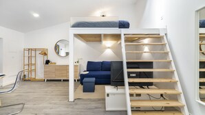 Ein kleines Zimmer mit Etagenbett, Schreibtisch, Stuhl, Fernseher und einer Stehle.