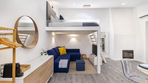 Ein moderner, kompakter Wohnraum mit Etagenbett, einer Couch, einer Kaffeemaschine und einem Fernseher.