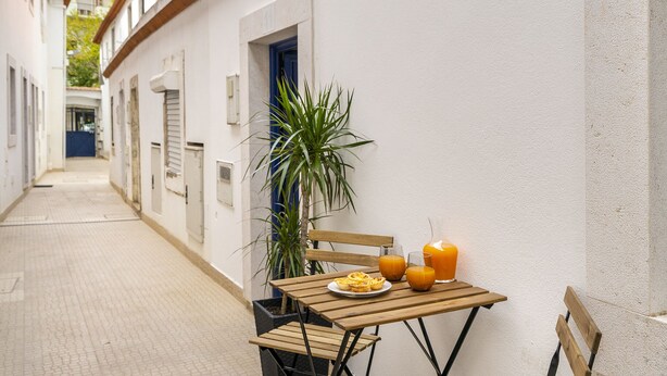 Eine schmale Straße mit einem für das Frühstück gedeckten Tisch, darunter Speisen und Getränke, sowie einem Blumentopf.