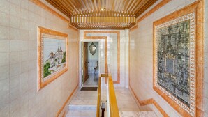 Un pasillo con paredes de baldosas, techo de madera y una escalera con barandilla.