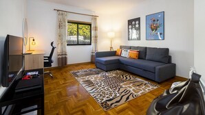 Una sala de estar con un sofá, un televisor, una lámpara y obras de arte en la pared.