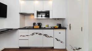A modern kitchen with white cabinets, a stainless steel microwave, and a black countertop. - Alfama Studio Prime Location Explore Lisbon W/ Style (Lisbon)