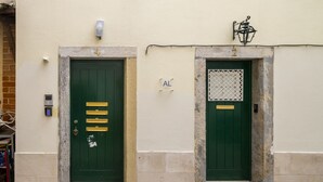 Two green doors with numbers 4 and 2, a small sign with 'AL', and a wall-mounted light fixture. - Alfama Studio Prime Location Explore Lisbon W/ Style (Lisbon)