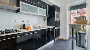 Een moderne keuken met zwarte kastjes, een roestvrijstalen fornuis en een raam met uitzicht op een balkon.